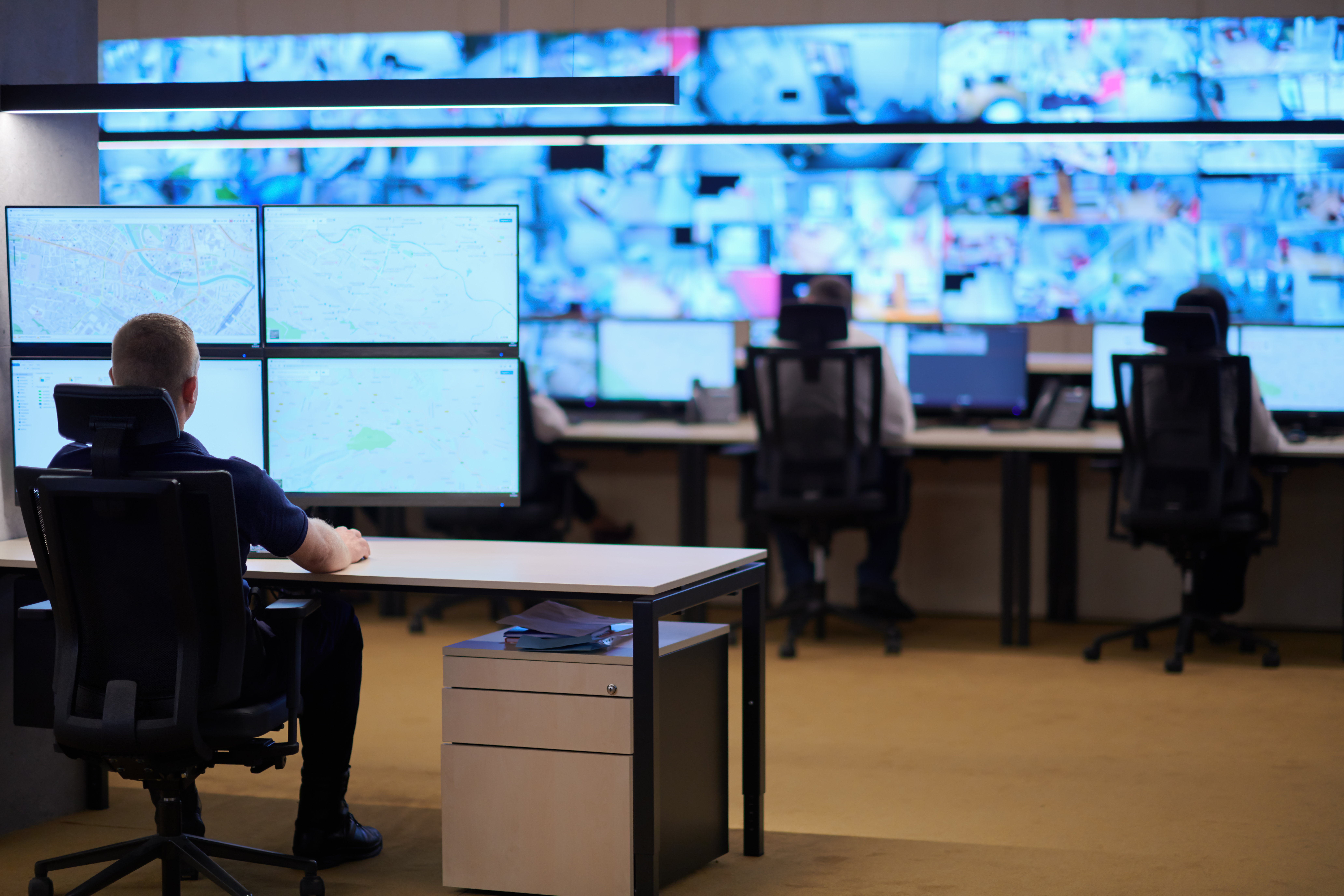 Male security operator working in a data system control room offices Technical Operator Working at  workstation with multiple displays, security guard working on multiple monitors  Male computer operator monitoring from a security center
