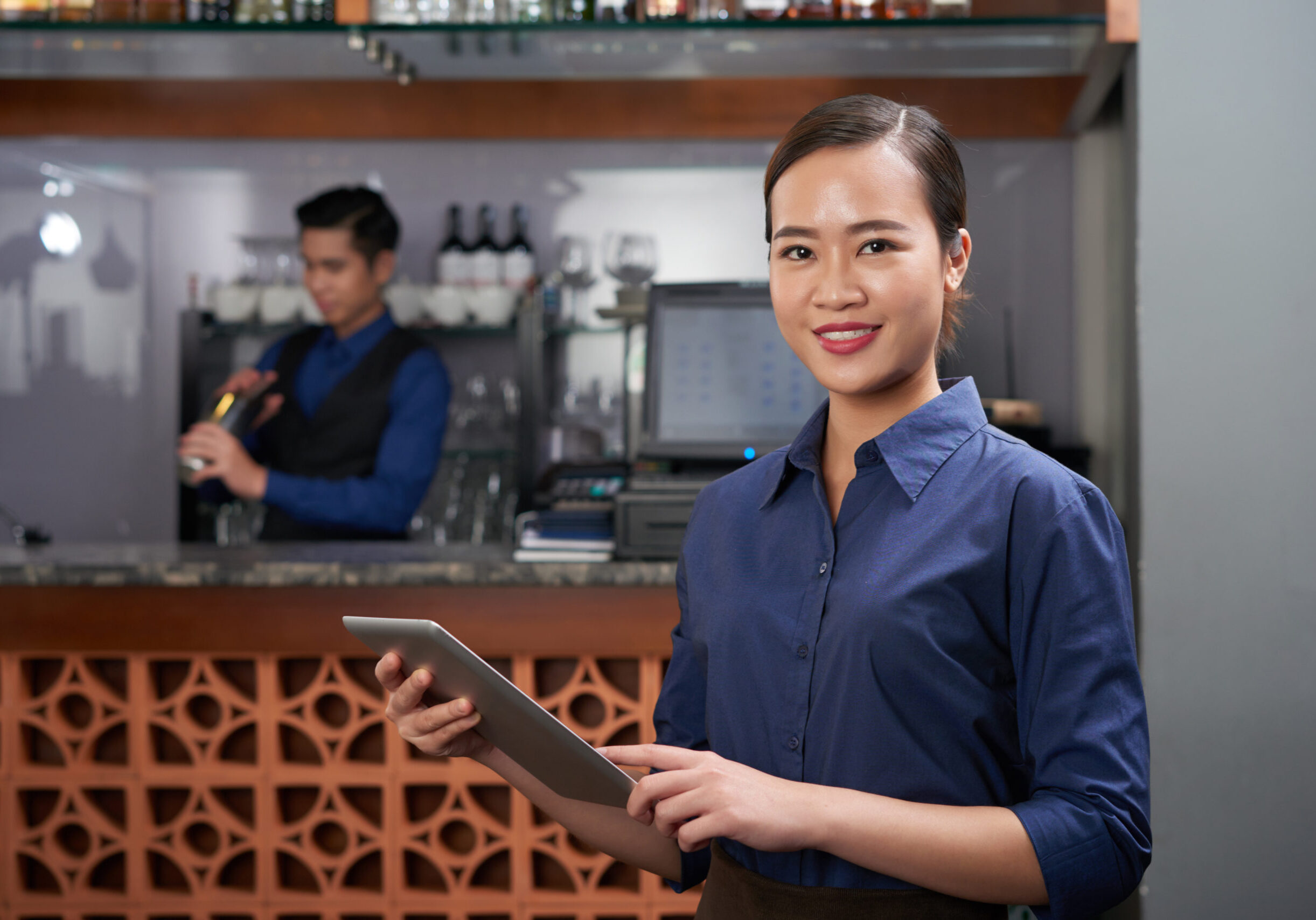 Pretty Vietnamese bar owner with tablet computer in her hands